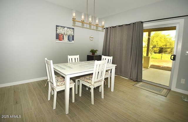 dining space with baseboards, light wood-type flooring, and an inviting chandelier