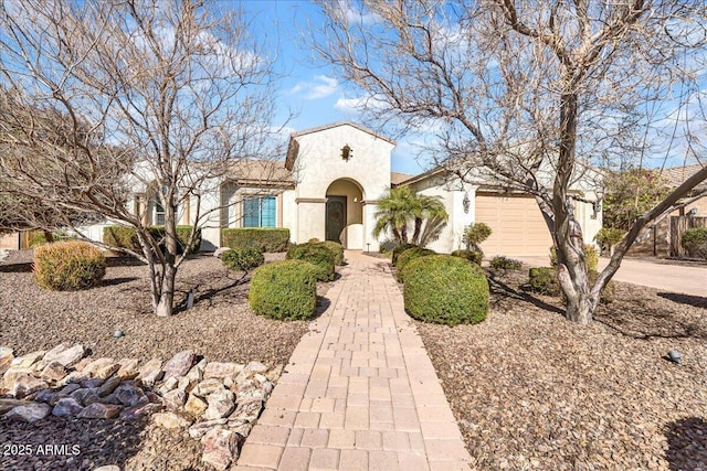 mediterranean / spanish home featuring a garage, driveway, and stucco siding