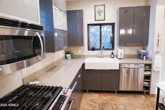 kitchen with stainless steel appliances, gray cabinetry, and sink