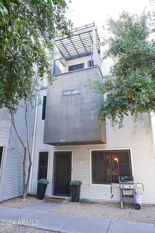 view of front of property with a pergola and a balcony