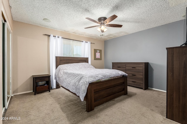 bedroom featuring a textured ceiling, ceiling fan, a closet, and light colored carpet