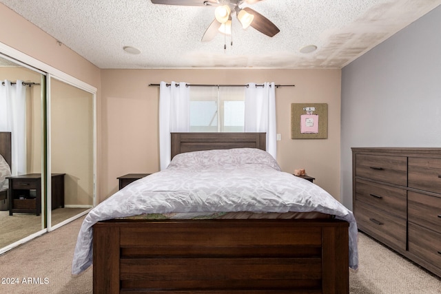 bedroom with ceiling fan, a textured ceiling, a closet, and light carpet