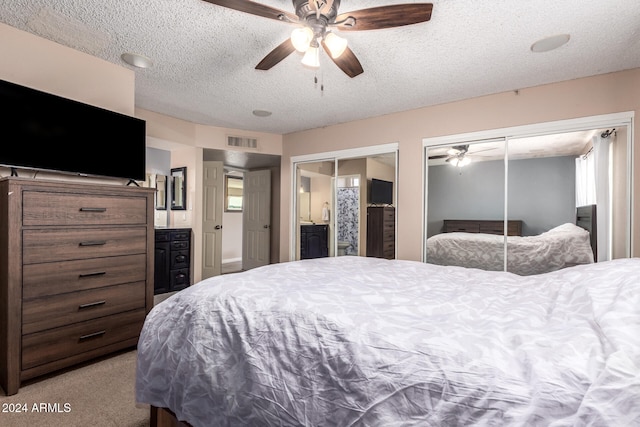 bedroom with light colored carpet, ensuite bath, a textured ceiling, and ceiling fan