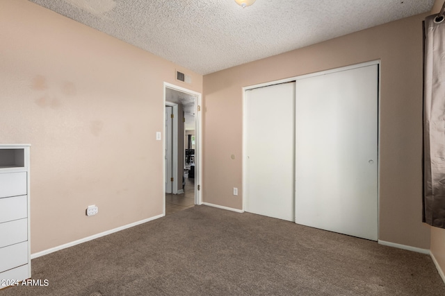 unfurnished bedroom with a closet, dark colored carpet, and a textured ceiling