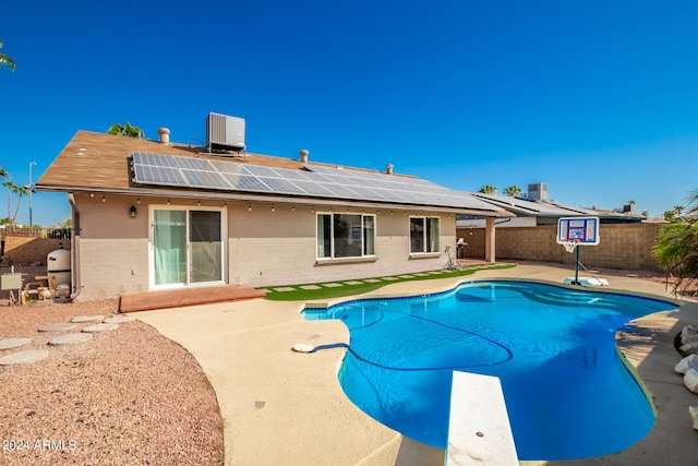 view of pool with a diving board, a patio, and central AC