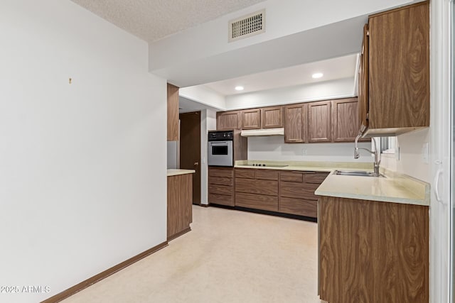 kitchen featuring black electric cooktop, sink, a textured ceiling, and stainless steel oven