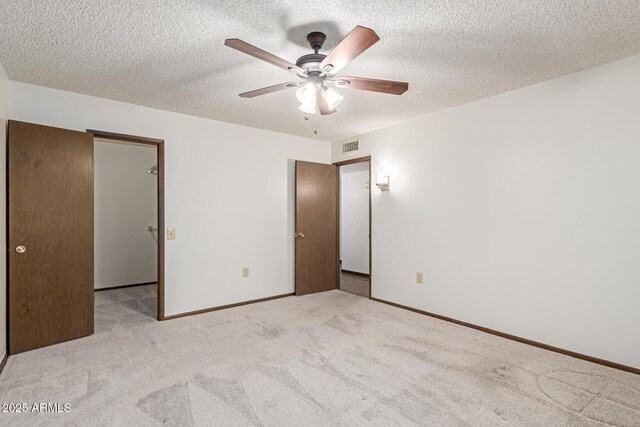 unfurnished bedroom featuring ceiling fan, light carpet, and a textured ceiling