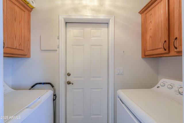 clothes washing area with cabinets and washing machine and clothes dryer