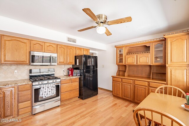3109 N 81st St, Scottsdale, AZ 85251 - kitchen with stainless steel appliances, glass insert cabinets, tasteful backsplash, light wood-style floors, and ceiling fan