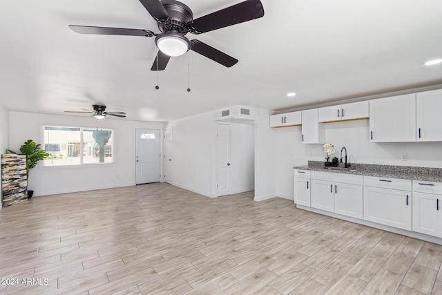 kitchen featuring white cabinets, light hardwood / wood-style flooring, sink, and light stone countertops