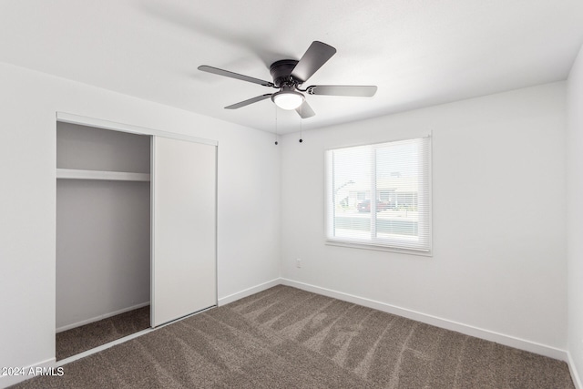 unfurnished bedroom with a closet, dark carpet, and ceiling fan