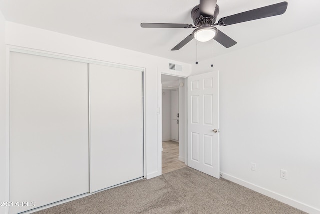 unfurnished bedroom with light carpet, ceiling fan, and a closet