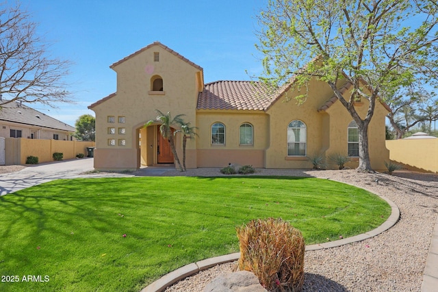 mediterranean / spanish home featuring a front lawn, stucco siding, a tile roof, and fence