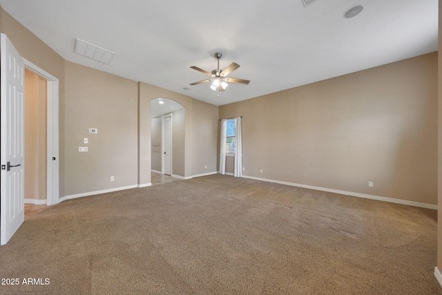 carpeted empty room featuring ceiling fan, arched walkways, visible vents, and baseboards