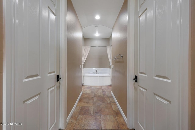 hallway with stone finish flooring and baseboards