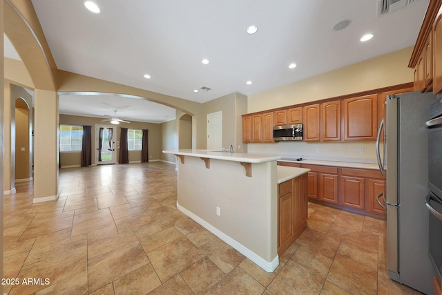 kitchen featuring arched walkways, visible vents, open floor plan, light countertops, and appliances with stainless steel finishes