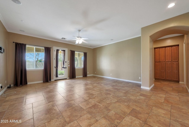 empty room featuring arched walkways, visible vents, crown molding, and baseboards