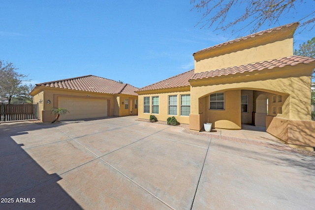 view of front of property with a garage, a tile roof, fence, driveway, and stucco siding