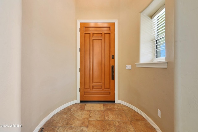 doorway to outside with elevator, stone finish flooring, and baseboards