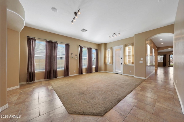 entrance foyer with arched walkways, light colored carpet, visible vents, baseboards, and track lighting