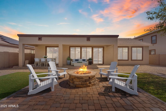 back of property at dusk with a patio area, stucco siding, a fire pit, and a fenced backyard