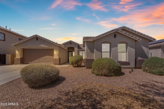 mediterranean / spanish house with an attached garage, stucco siding, driveway, and a tile roof