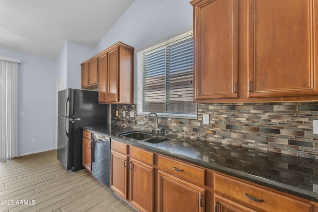kitchen featuring a sink, freestanding refrigerator, dishwashing machine, light wood-type flooring, and backsplash
