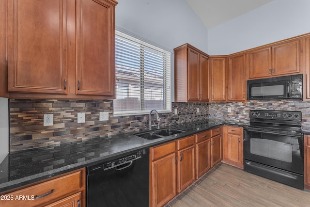 kitchen with black appliances, tasteful backsplash, dark stone countertops, and a sink