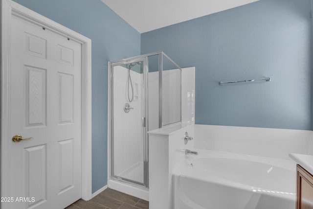 full bath with wood finished floors, vanity, a stall shower, baseboards, and a bath