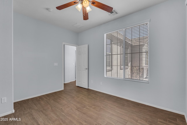 empty room featuring a wealth of natural light, ceiling fan, and wood finished floors