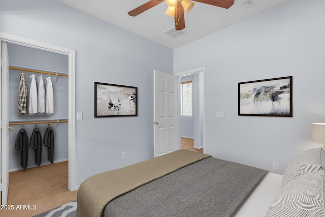 bedroom with carpet, a closet, a walk in closet, visible vents, and ceiling fan