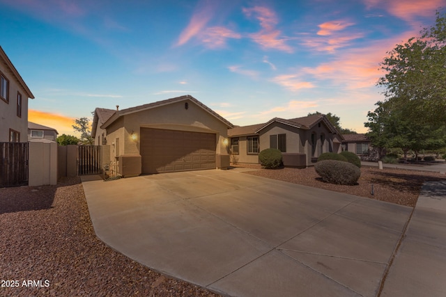 ranch-style home with a gate, fence, concrete driveway, a garage, and stucco siding