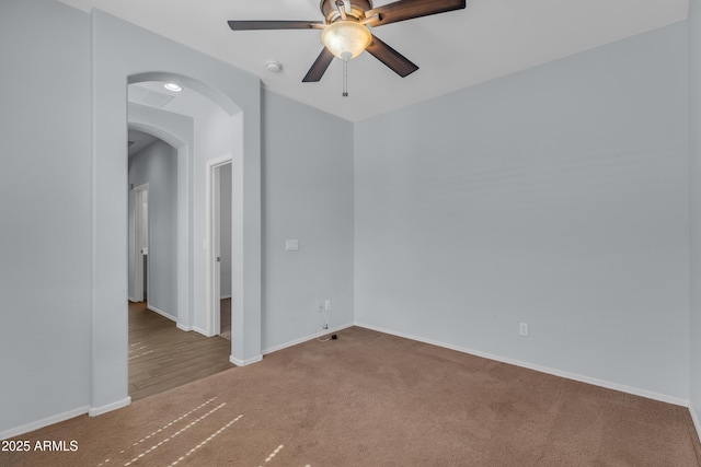 spare room with carpet, baseboards, a ceiling fan, and arched walkways