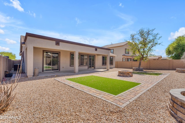 back of house with a fenced backyard, stucco siding, and a fire pit