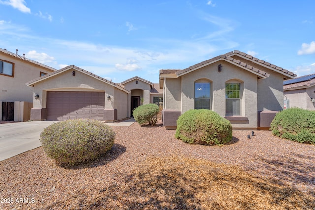 mediterranean / spanish home featuring an attached garage, concrete driveway, stucco siding, and a tiled roof