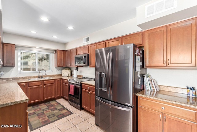 kitchen featuring appliances with stainless steel finishes, light stone countertops, sink, and light tile patterned floors