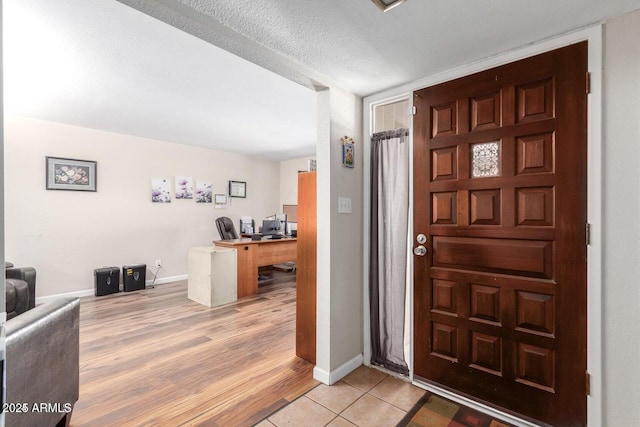 foyer with a textured ceiling and light tile patterned floors