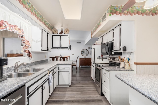 kitchen with a sink, stainless steel appliances, white cabinetry, and light countertops