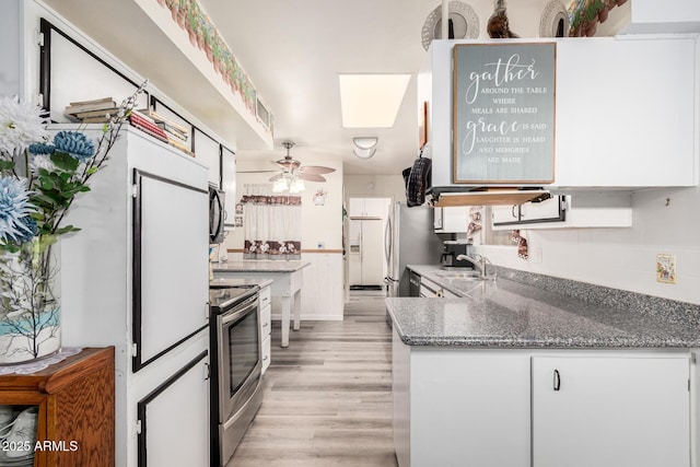 kitchen featuring ceiling fan, light wood-type flooring, appliances with stainless steel finishes, white cabinets, and a sink