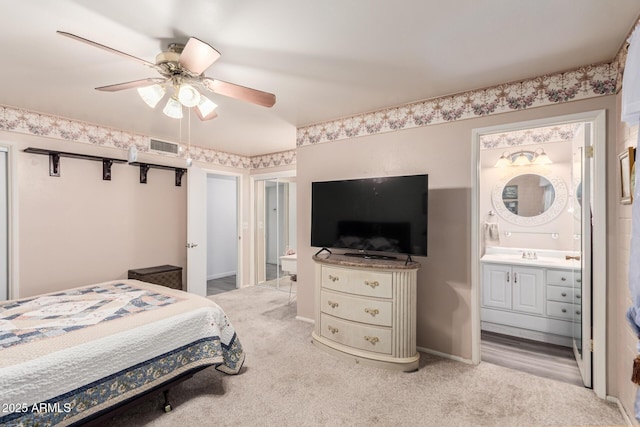 bedroom with a sink, ensuite bath, visible vents, and light carpet