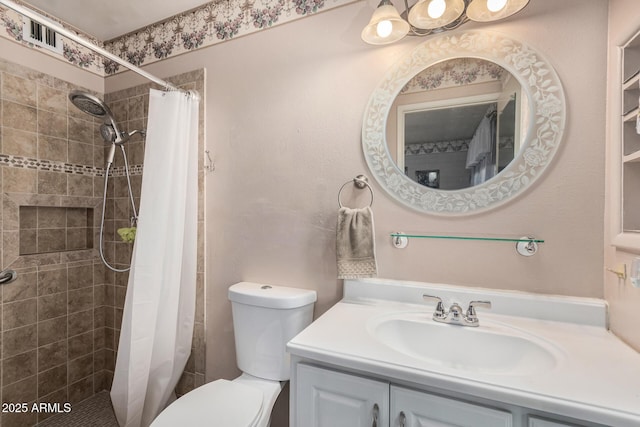 full bathroom featuring tiled shower, toilet, and vanity