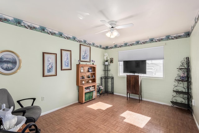 living area featuring baseboards and ceiling fan