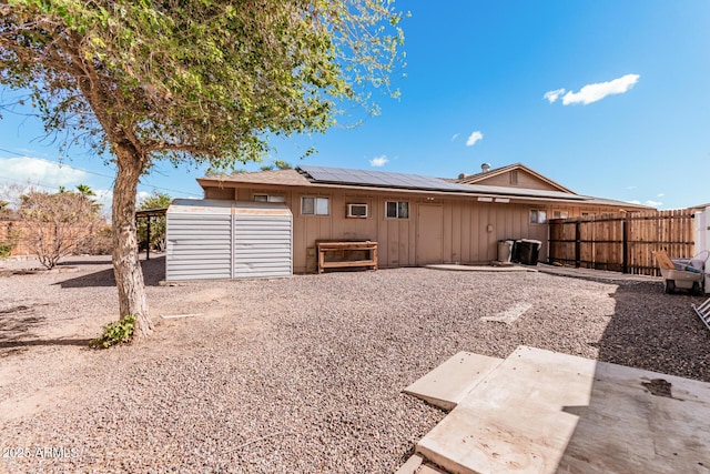 rear view of house featuring fence, solar panels, and a patio area