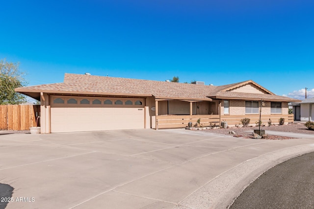 ranch-style home with brick siding, driveway, an attached garage, and fence