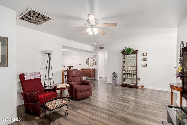 living area with visible vents, baseboards, a ceiling fan, and wood finished floors