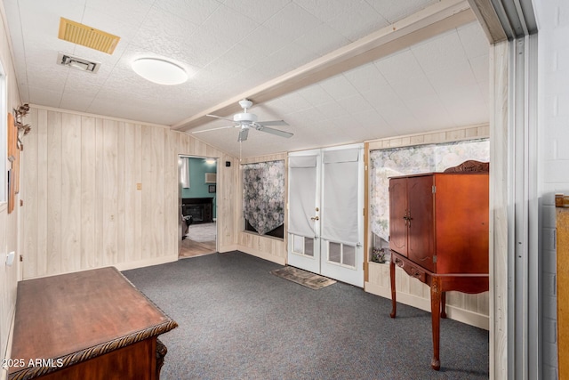 interior space with visible vents, wooden walls, ceiling fan, and vaulted ceiling with beams