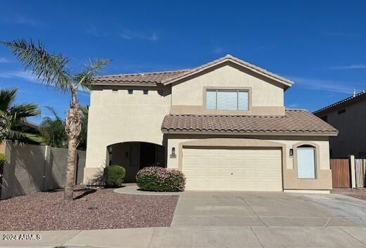 mediterranean / spanish home with an attached garage, fence, a tiled roof, stucco siding, and driveway