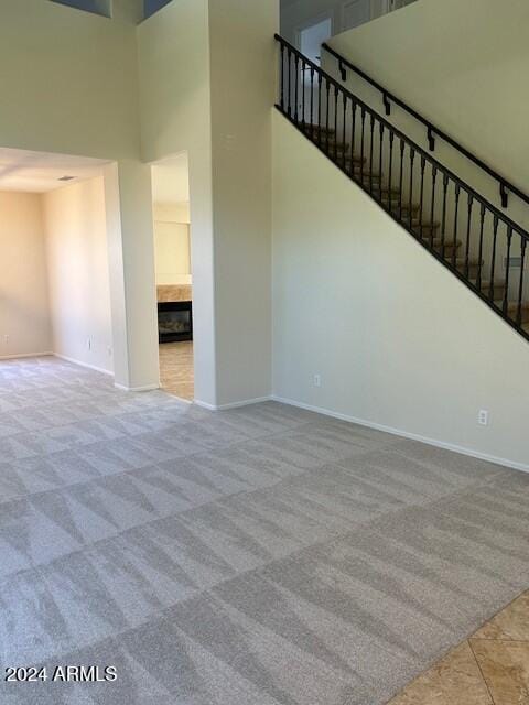 unfurnished living room with baseboards, carpet floors, and a high ceiling