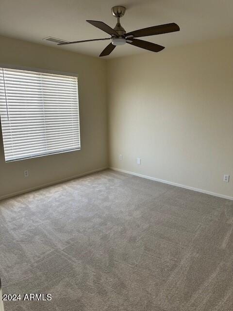 spare room with carpet, visible vents, a ceiling fan, and baseboards