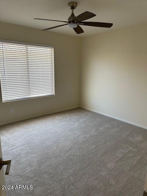 carpeted empty room featuring baseboards and ceiling fan